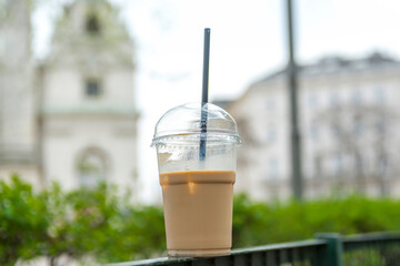 Disposable coffee cup with city view on background.