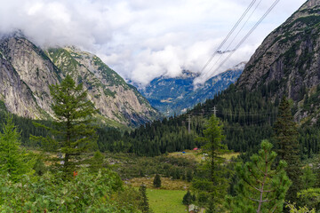 Obraz premium Alpine landscape in the Swiss Alps with fog and peak at mountain pass Grimsel on a cloudy late summer day. Photo taken September 19th, 2023, Grimsel, Canton Bern, Switzerland.