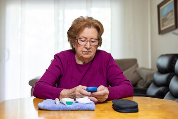 Elderly woman checking blood sugar levels at home