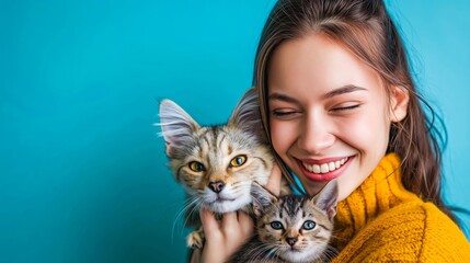 Portrait of a happy woman with cute cats isolated on a blue background, a smiling young female holding playful kittens