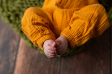small children's legs in yellow pants on a dark background. small fingers