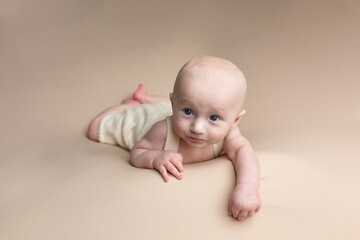 baby lies on a beige surface with blue eyes
