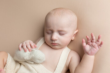 a small child with a toy lies on a light background. newborn boy. baby's first photo shoot