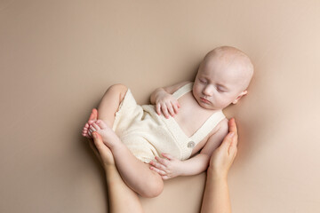 a small child lies on a light background. newborn boy in mother's hands. baby's first photo shoot