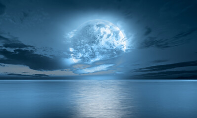 Night sky with blue moon in the clouds over the calm blue sea 