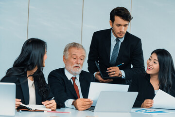 Senior caucasian manager working in office with assistance of young Asian business people and...