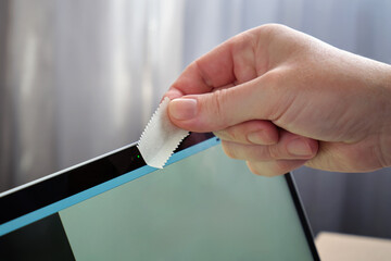Close-up of a male hand covering the webcam on a laptop with a piece of paper.