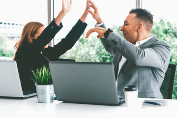 Success business partner - Businesswoman and businessman celebrating together in modern workplace...