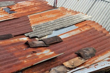 Top view The tin roof or zinc roof that has been damaged, rusty and has holes due to age and weather. High angle aerial Aged building roof.