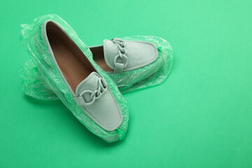 Women's mules in shoe covers on green background, closeup. Space for text