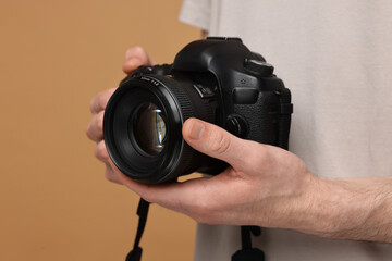 Photographer holding camera on beige background, closeup