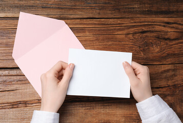 Obraz premium Woman with blank card at wooden table, top view. Space for text