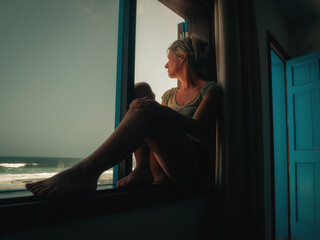 Woman sitting on a window looking at the sea