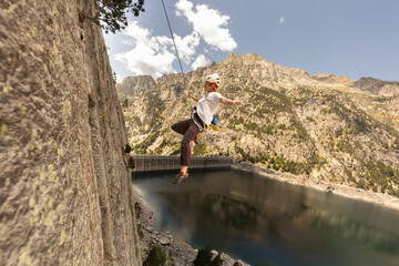 A man is jumping off a cliff into a lake