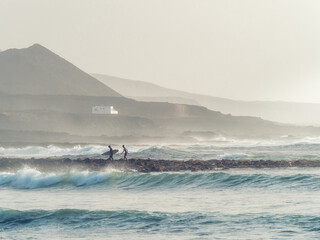 Surfers returning tired to the beach amidst the waves