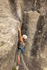 A woman is climbing a rock wall with a helmet on