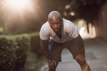African American man catching breath after morning run in park