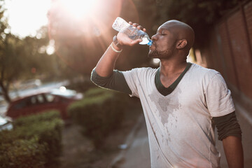 African American man drinking water after outdoor exercise session