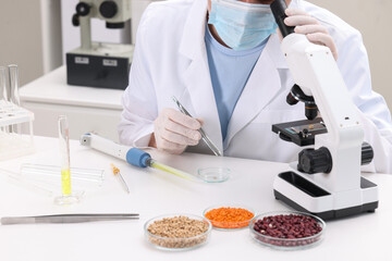 Quality control. Food inspector examining wheat grain under microscope in laboratory, closeup