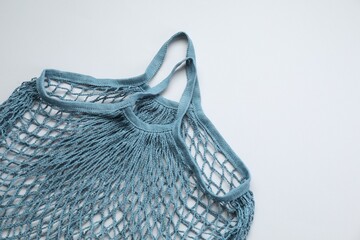 Blue string bag on light grey background, top view