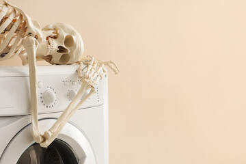 Waiting concept. Human skeleton lying on washing machine near beige wall indoors, space for text