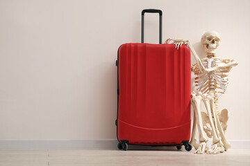 Waiting concept. Human skeleton with suitcase near light grey wall, space for text