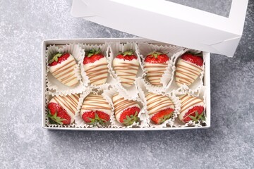 Box with delicious chocolate covered strawberries on light grey table, top view