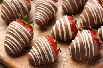Delicious chocolate covered strawberries on wooden board, closeup