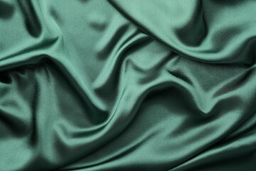 Fototapeta premium Crumpled green silk fabric as background, top view