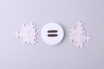 Puzzle pieces and equals sign on light background, flat lay