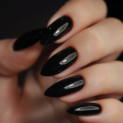 A close-up of perfectly manicured hands featuring glossy black, almond-shaped nails. The high-shine finish highlights the sleek and sophisticated look