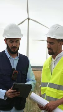 Team of technical workers and engineer working in wind turbine electricity farm, planing renewable energy project
