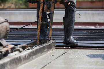 Construction worker operating machine spreading wet concrete pouring at precast concrete wall construction site. Worker or mason working or making smooth surface of concrete with machine at site work