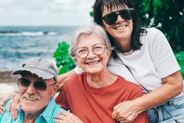 Cheerful group of senior friends enjoying sea holidays sitting together looking at camera smiling - travel and vacation, carefree retirement lifestyle concept