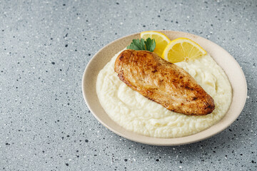 delicious mashed cauliflower and fried chicken breast on a light stone background