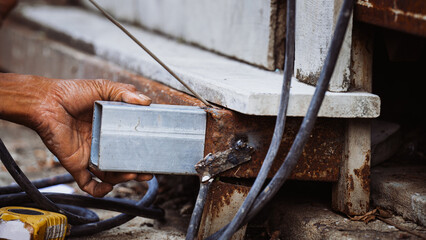 Closeup of a mechanic's hand welding steel during the summer.