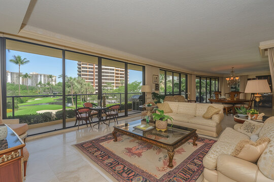 Living room with expansive windows offering a view of lush green golf course outside