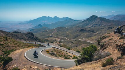 Motorcyclists navigating hairpin turns on a mountain pass road, with clear blue skies overhead.