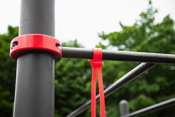 Elastic rubber band for exercise tied on a horizontal bar . Outdoor gym concept . Close up view