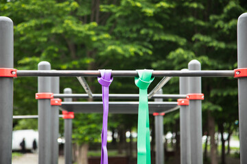 Purple and green Elastic rubber bands for exercise tied on a horizontal bar . Horizontal shot