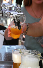 bartender pouring fresh lager beer from a tap  at a pub with a waitres