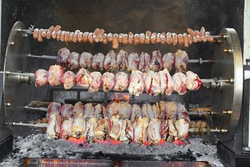 rotisserie with pork and sausages cooking over the open flames of an outdoor restaurant