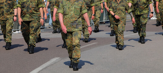 platoon of army soldiers marching down a city street in camouflage uniforms