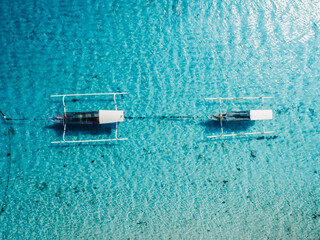 Motor boats in blue transparent sea in tropical island. Drone top down view.