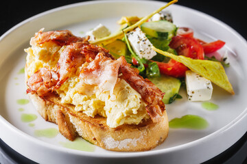 toast with scramble and bacon on a white plate