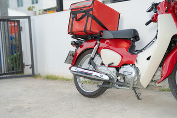 Red delivery motorcycle with insulated food box parked outdoors