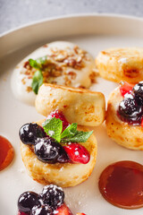cottage cheese pancakes with berries and jam on a white plate