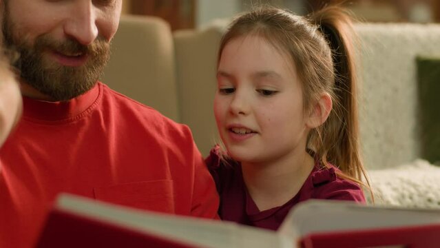 Caucasian family read book together at evening home smiling man parent dad babysitter father help children kids daughters with homework little school girls reading learn knowledge elementary education
