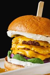 a delicious cheeseburger with three beef cutlets and a cheese bath