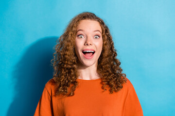 Photo portrait of youth beautiful funny girl with curly hair wearing orange t shirt amazed reaction isolated on blue color background